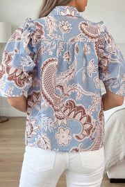 Blue cotton button-up shirt with floral pattern and ruffled sleeves.