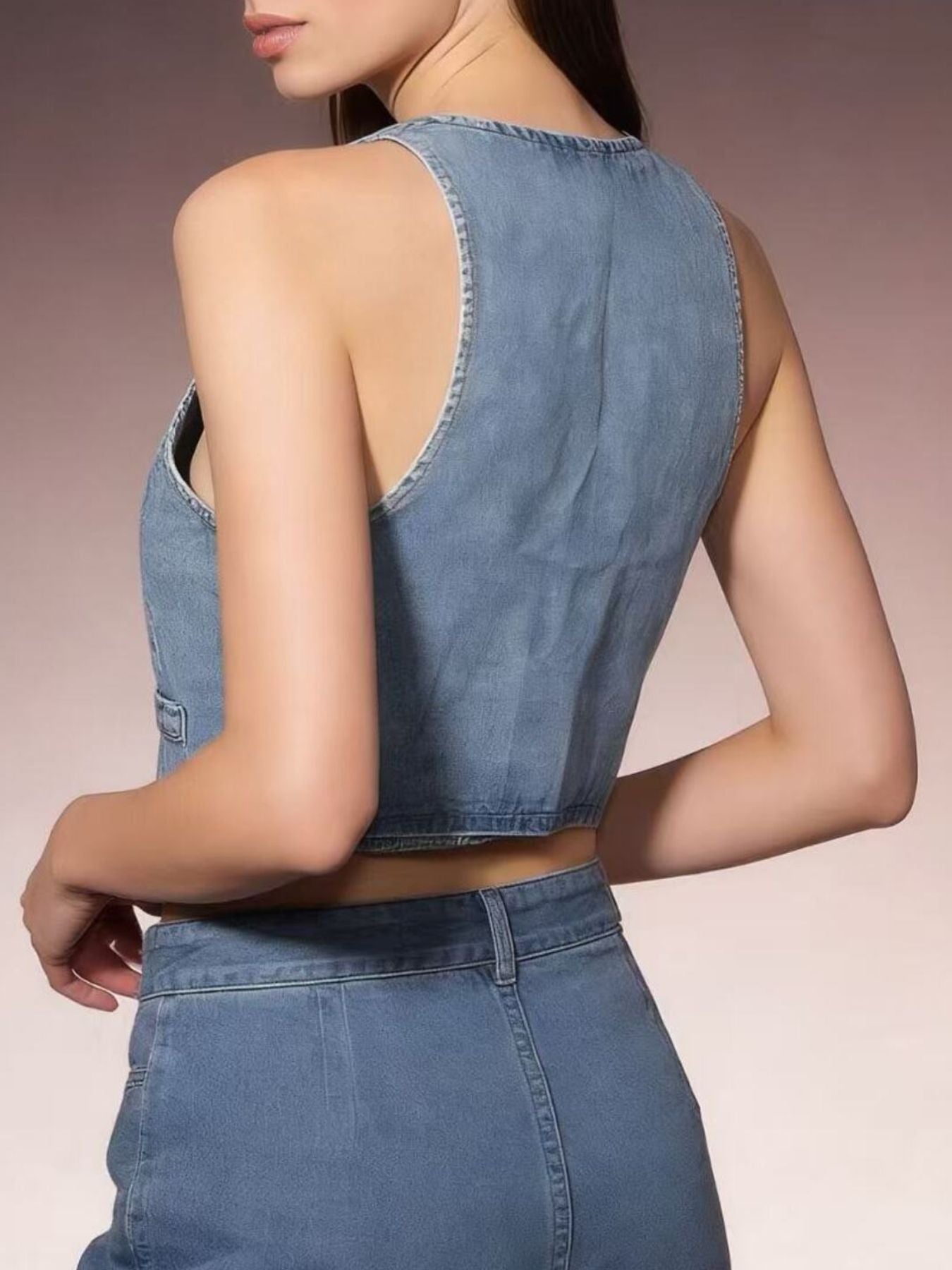 Light blue cropped denim vest with button-down front and raw hem.