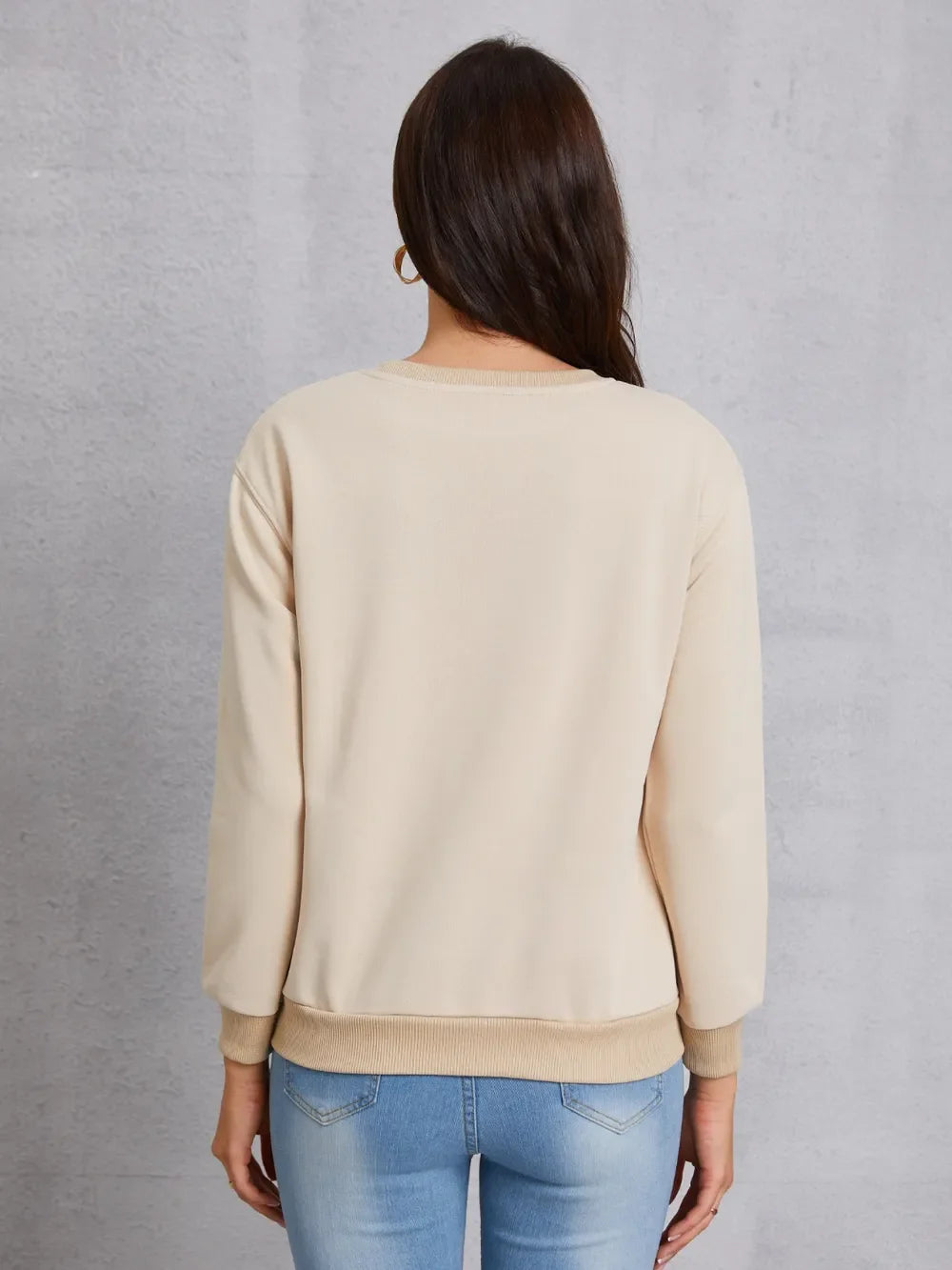 Khaki sweatshirt with crew neck and ribbed cuffs and hem, worn with jeans.