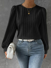 Black pleated blouse with gathered shoulders and long sleeves.