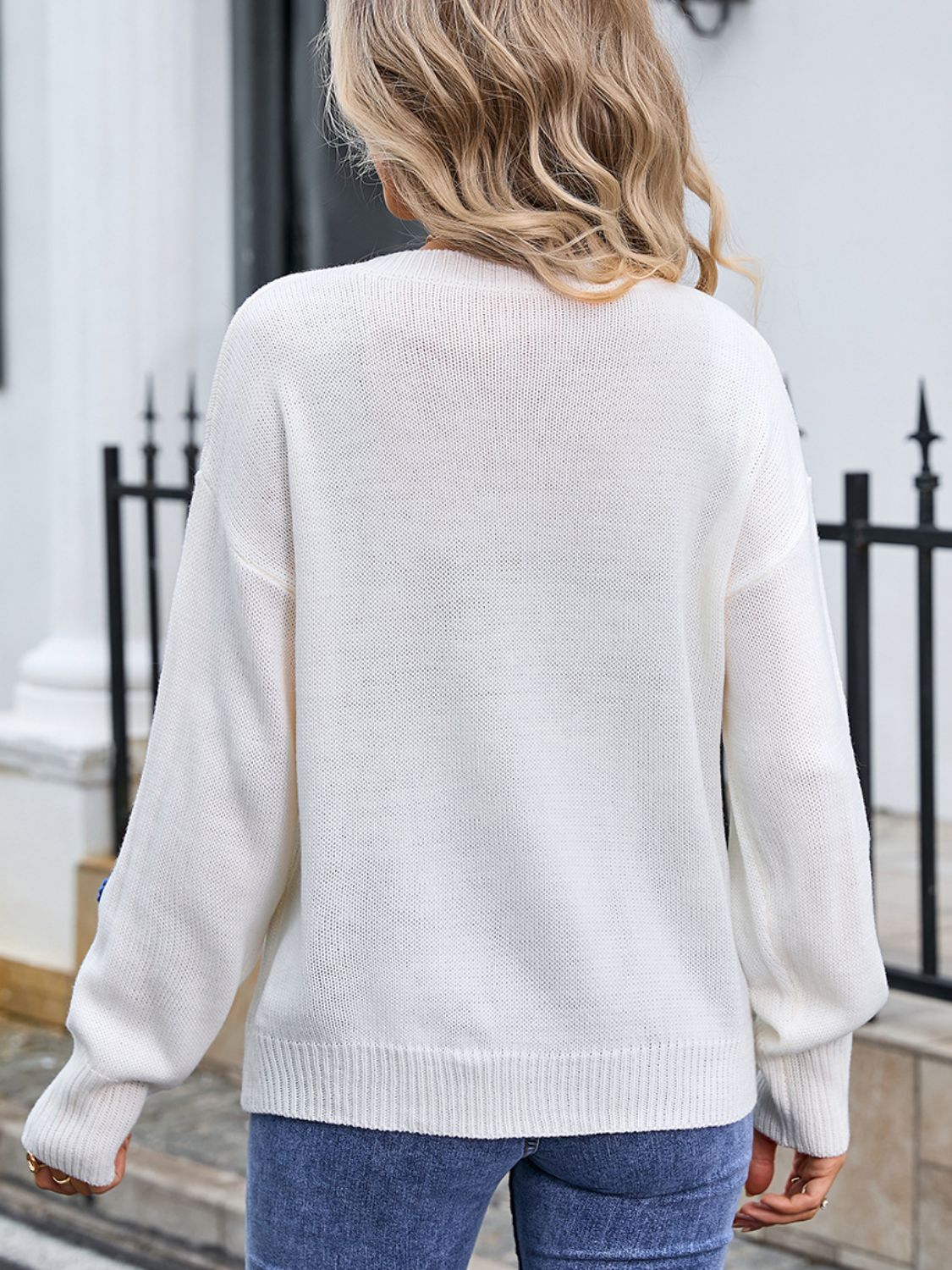 White knit sweater with embroidered bloom appliqué detail on sleeve