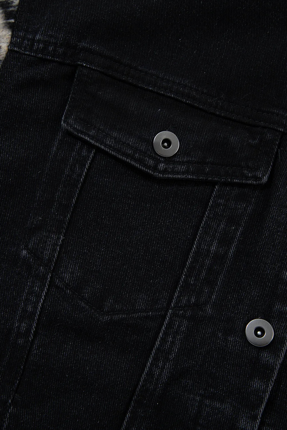 Black denim trucker jacket with snap button chest pockets and metal hardware.