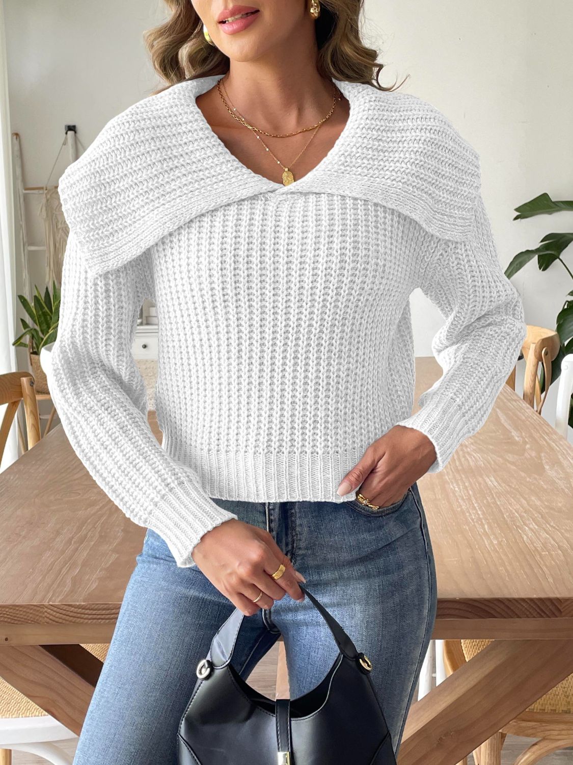 White ribbed knit sweater with shawl collar and long sleeves, styled with jeans and a black handbag.