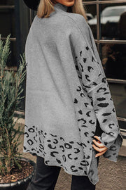 Gray knit sweater with asymmetric leopard print panels on sleeves and hem.