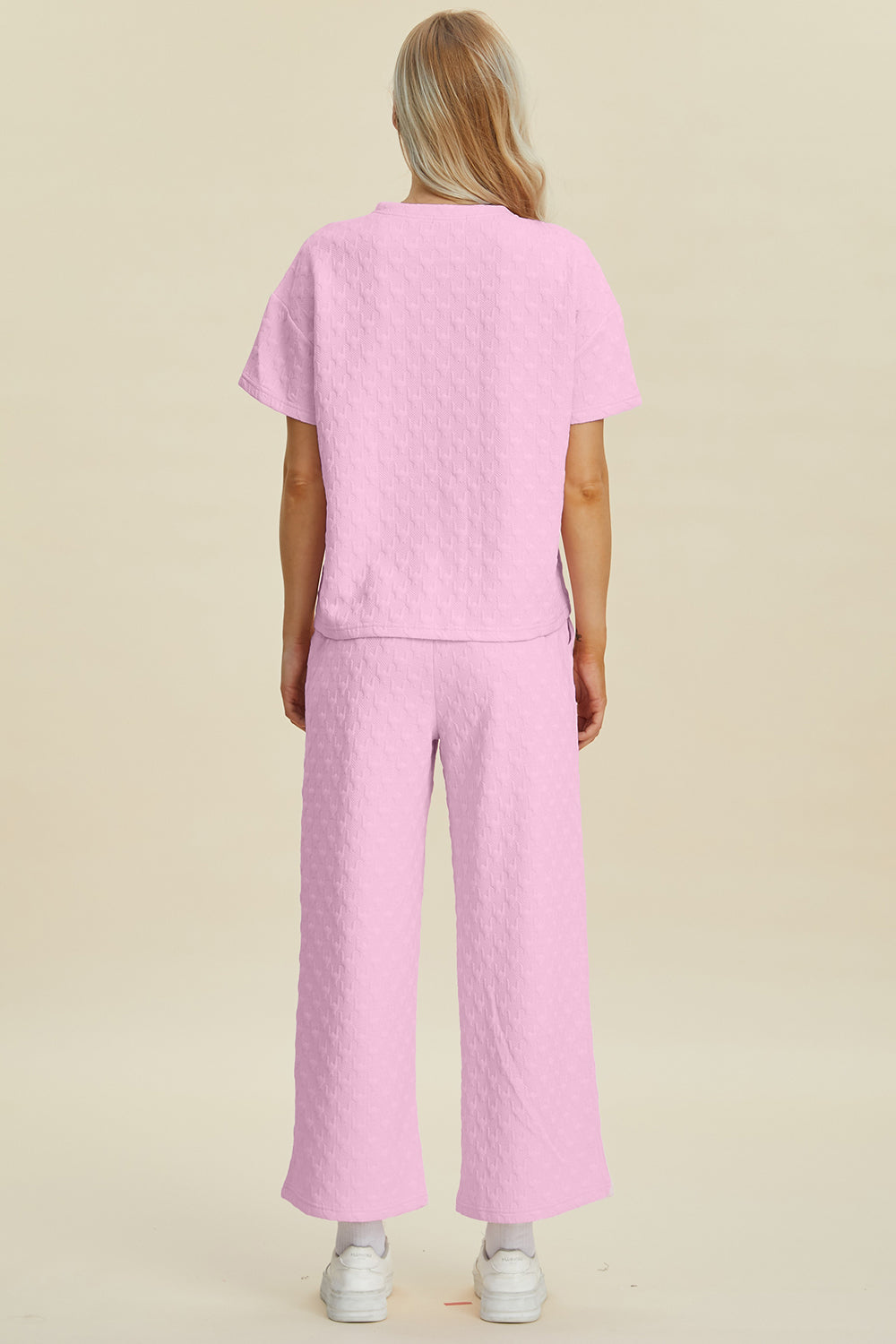 Pink textured knit lounge set with wide leg pants and short sleeve top.