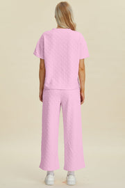 Pink textured knit lounge set with wide leg pants and short sleeve top.