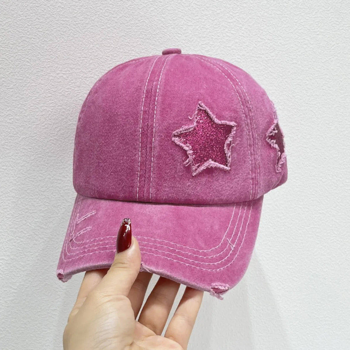 Hot pink baseball cap with glitter star patches and distressed details.