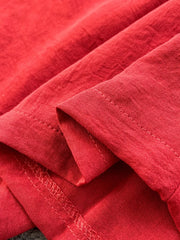 Red belted wide leg romper detail showing textured fabric and stitching.