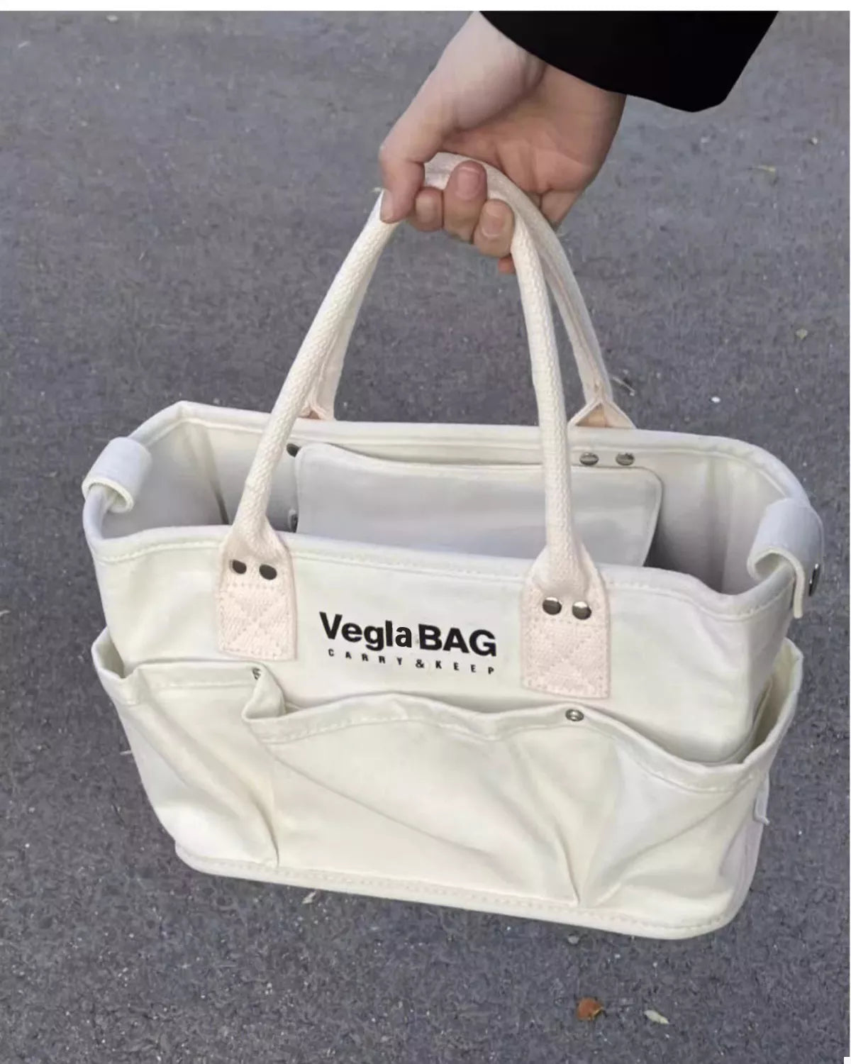 Beige canvas shopper bag with multiple exterior pockets and rope handles.
