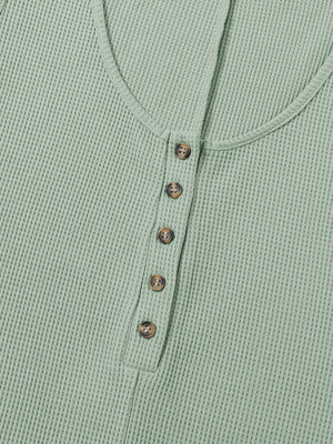 Sage green waffle knit button-down romper with round neckline and brown buttons.