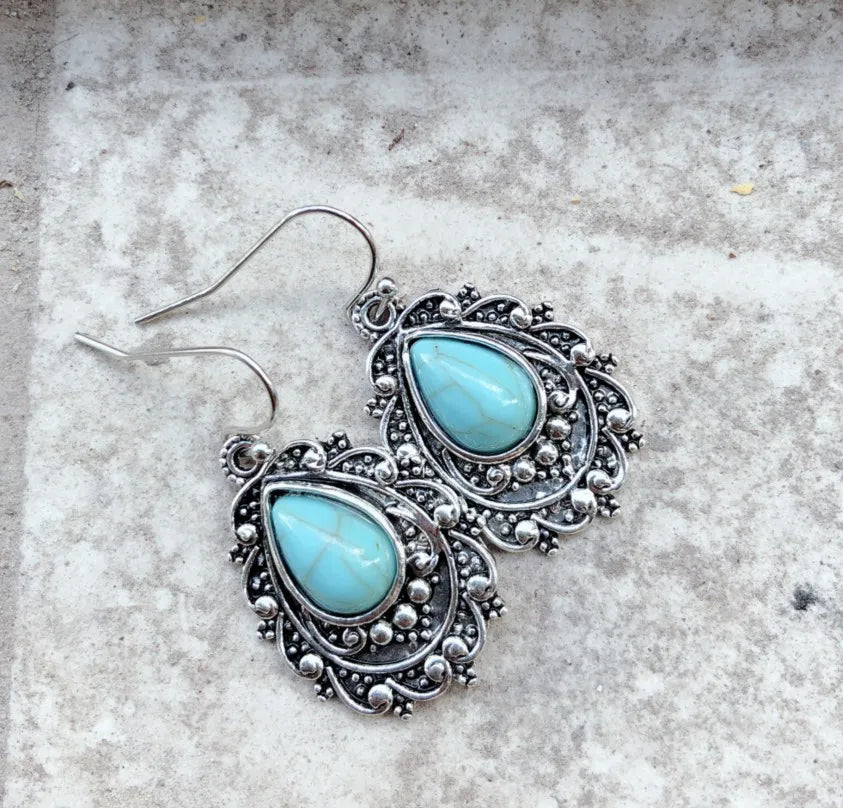 Turquoise teardrop filigree statement earrings with silver metalwork.