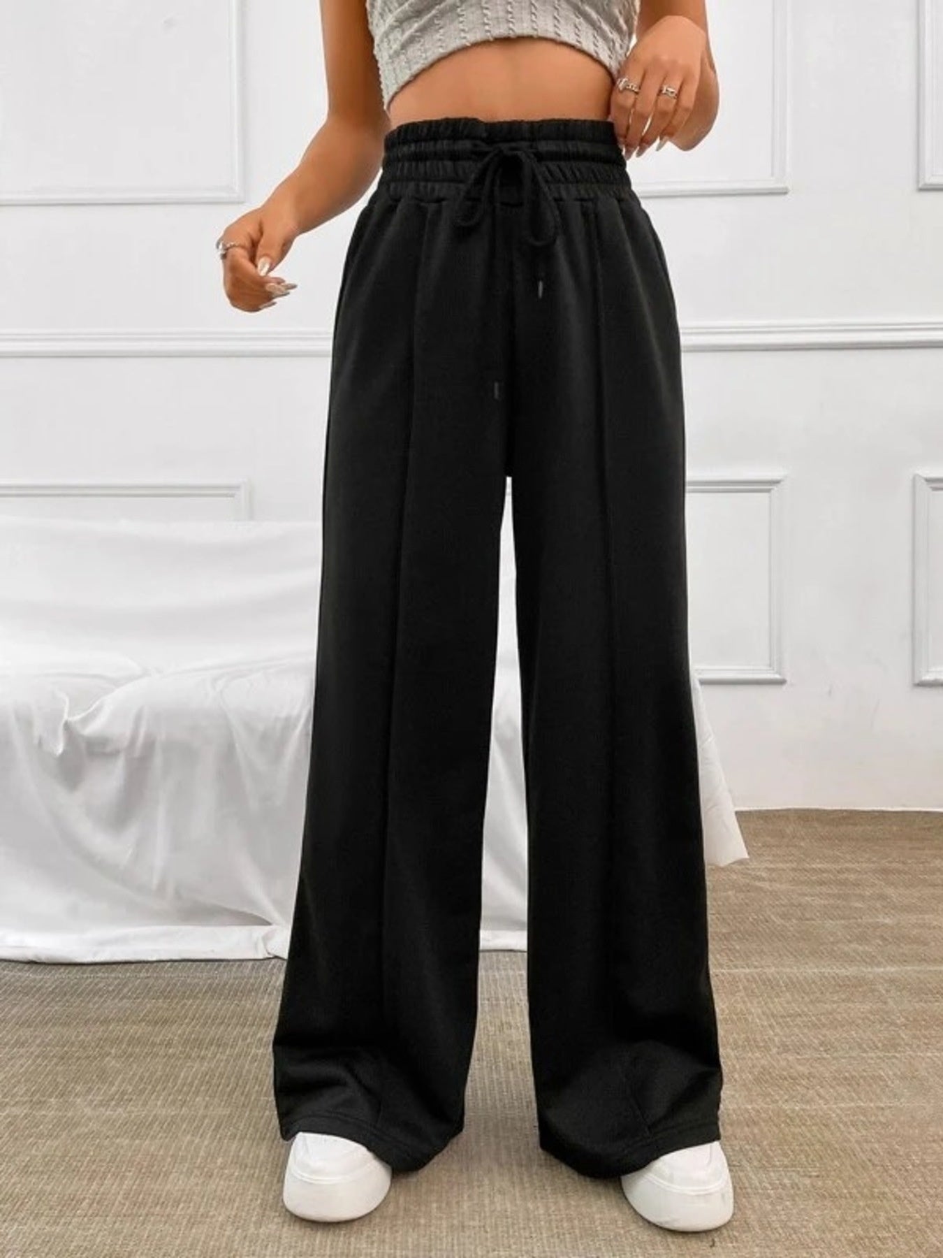 Black relaxed wide-leg sweatpants with drawstring waist and front seams.