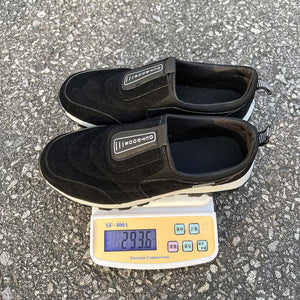 Black suede-like round toe slip-on sneakers with "OUTDOOR" detail.