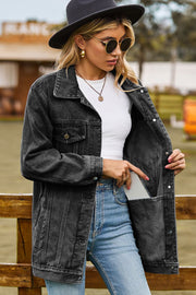 Black oversized denim trucker jacket with classic buttoned pockets and a phone in the side pocket.