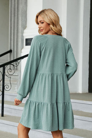 Light green textured babydoll mini dress with voluminous sleeves and tiered skirt.