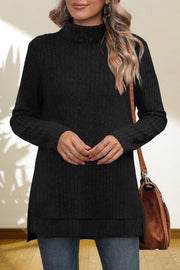 Black ribbed knit turtleneck tunic top with long sleeves and side slits, styled with a brown crossbody bag.