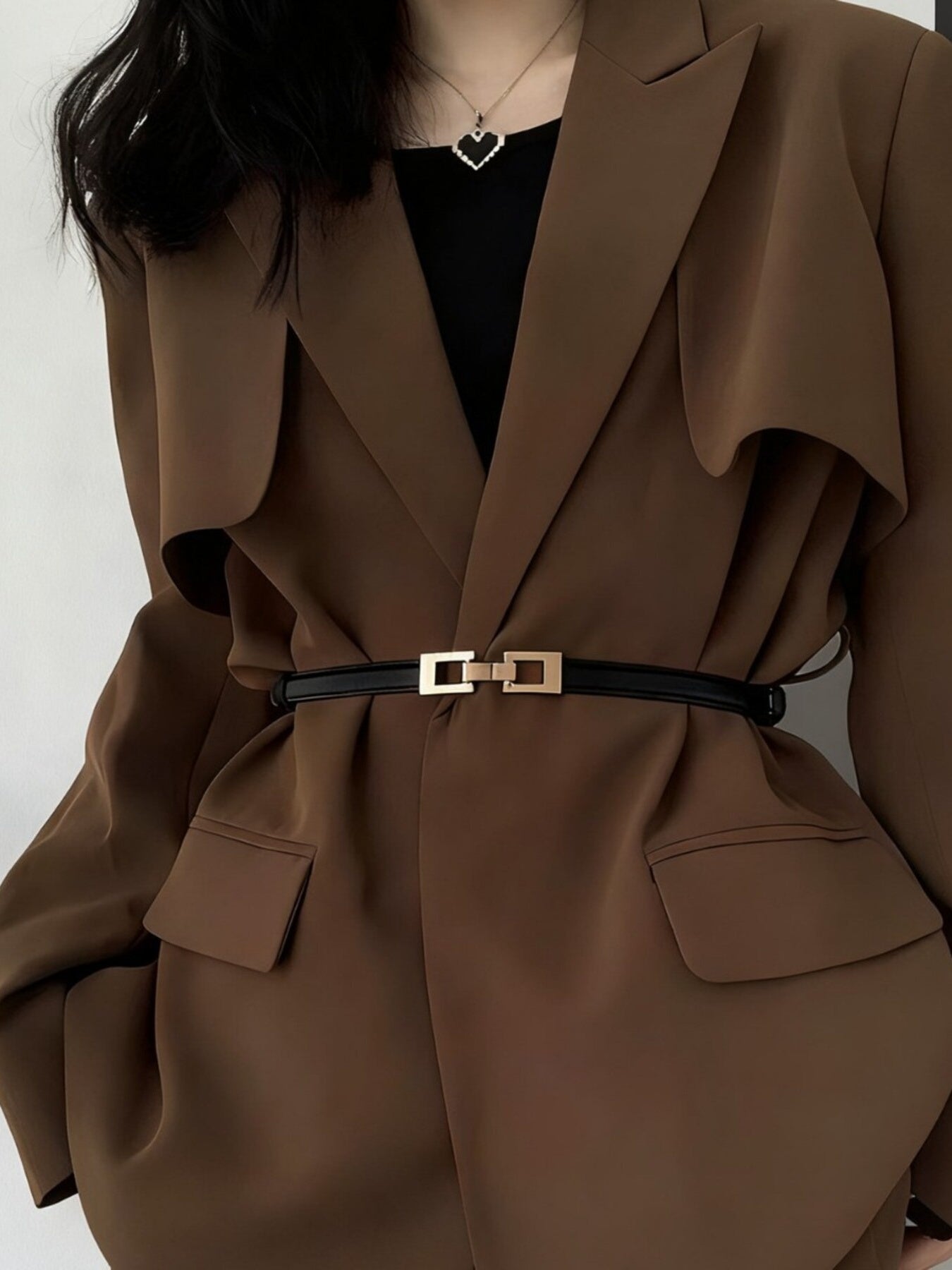 Black cowhide leather belt with a gold buckle cinching a brown blazer