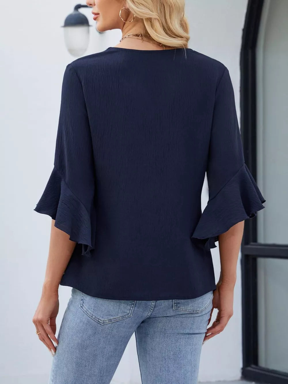 Navy V-neck blouse with ruffle sleeves and textured fabric.