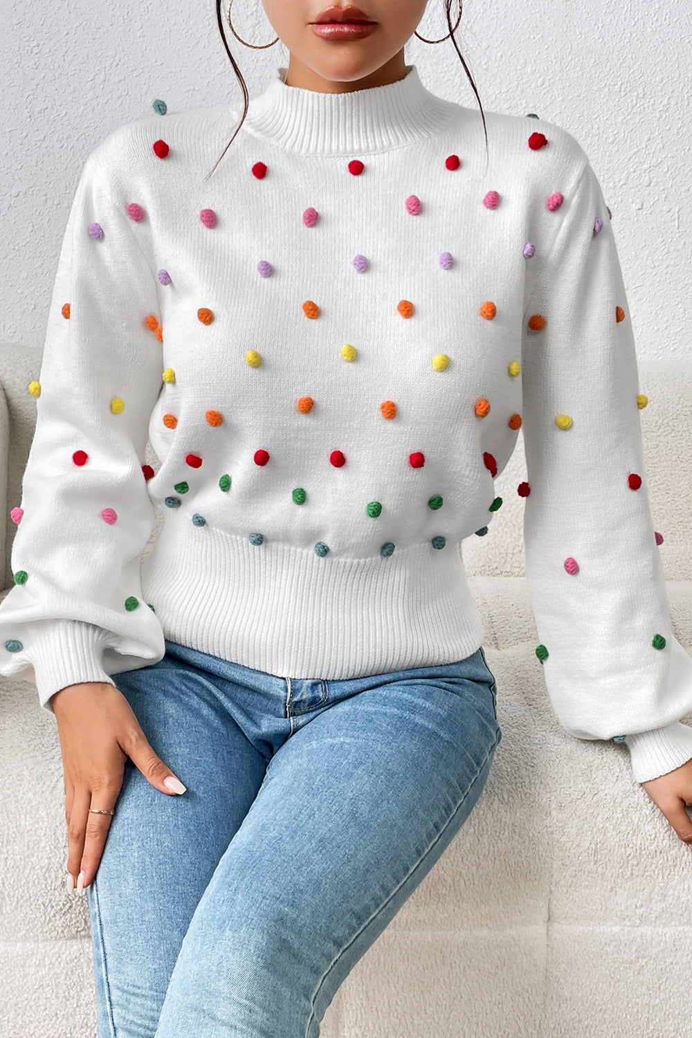 White knit sweater with colorful pom-pom embellishments and mock neck