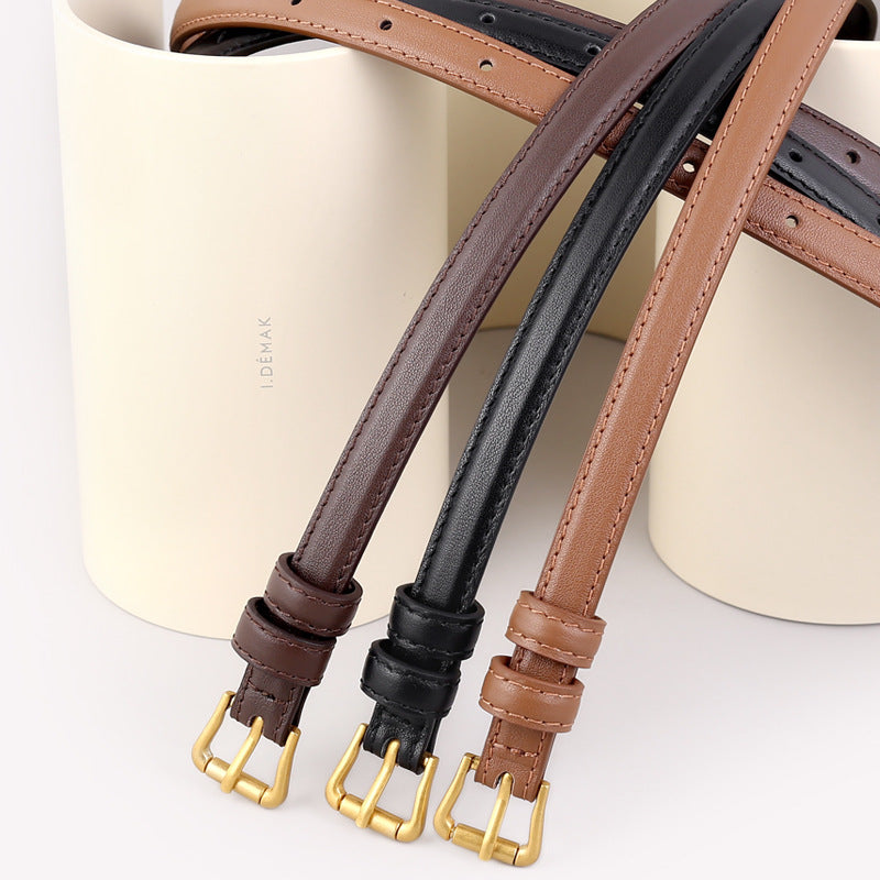 Elegant cowhide leather belts in black, caramel, and brown with gold buckles.