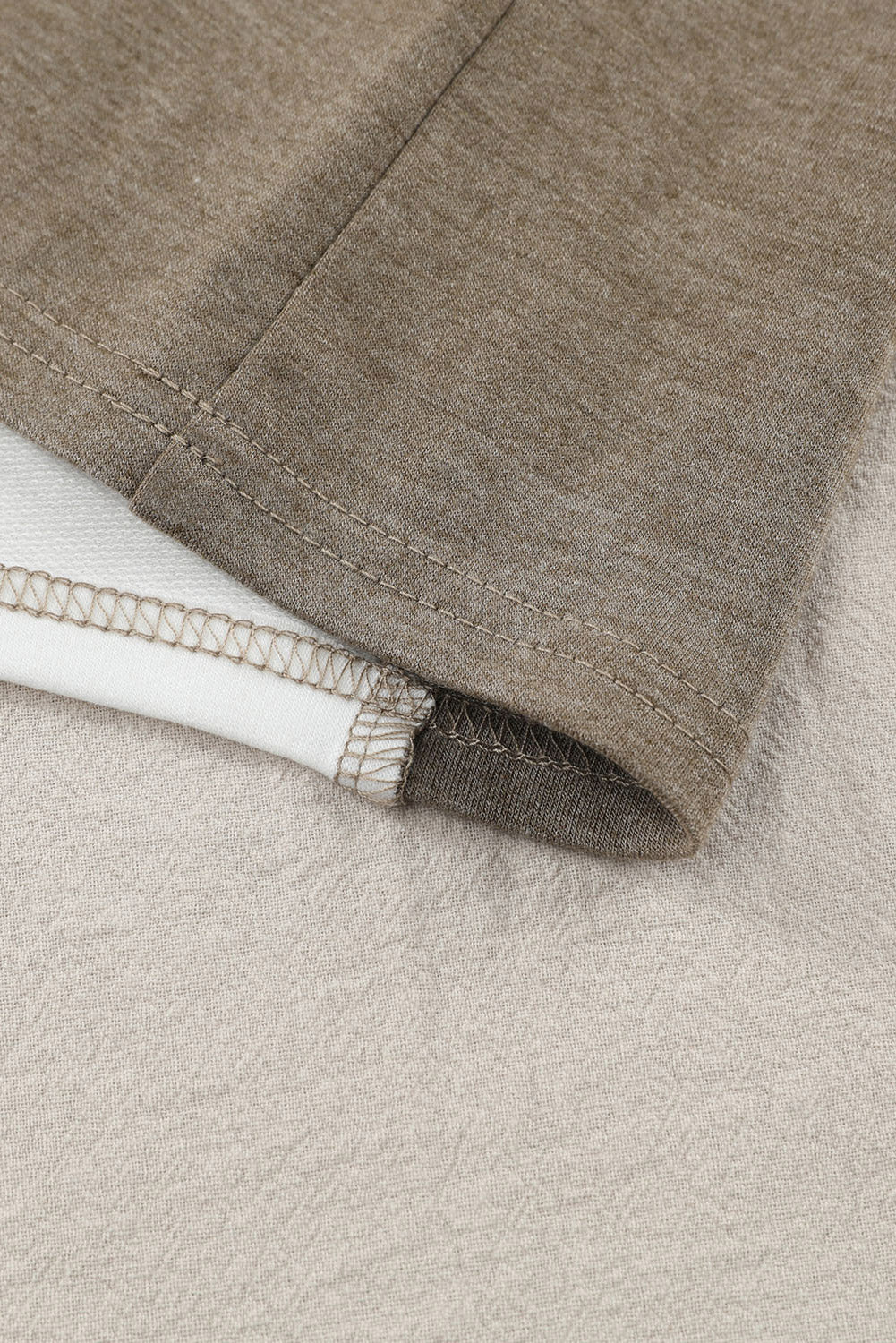 Colorblock knit top in tan showing seam detail and contrasting fabric.