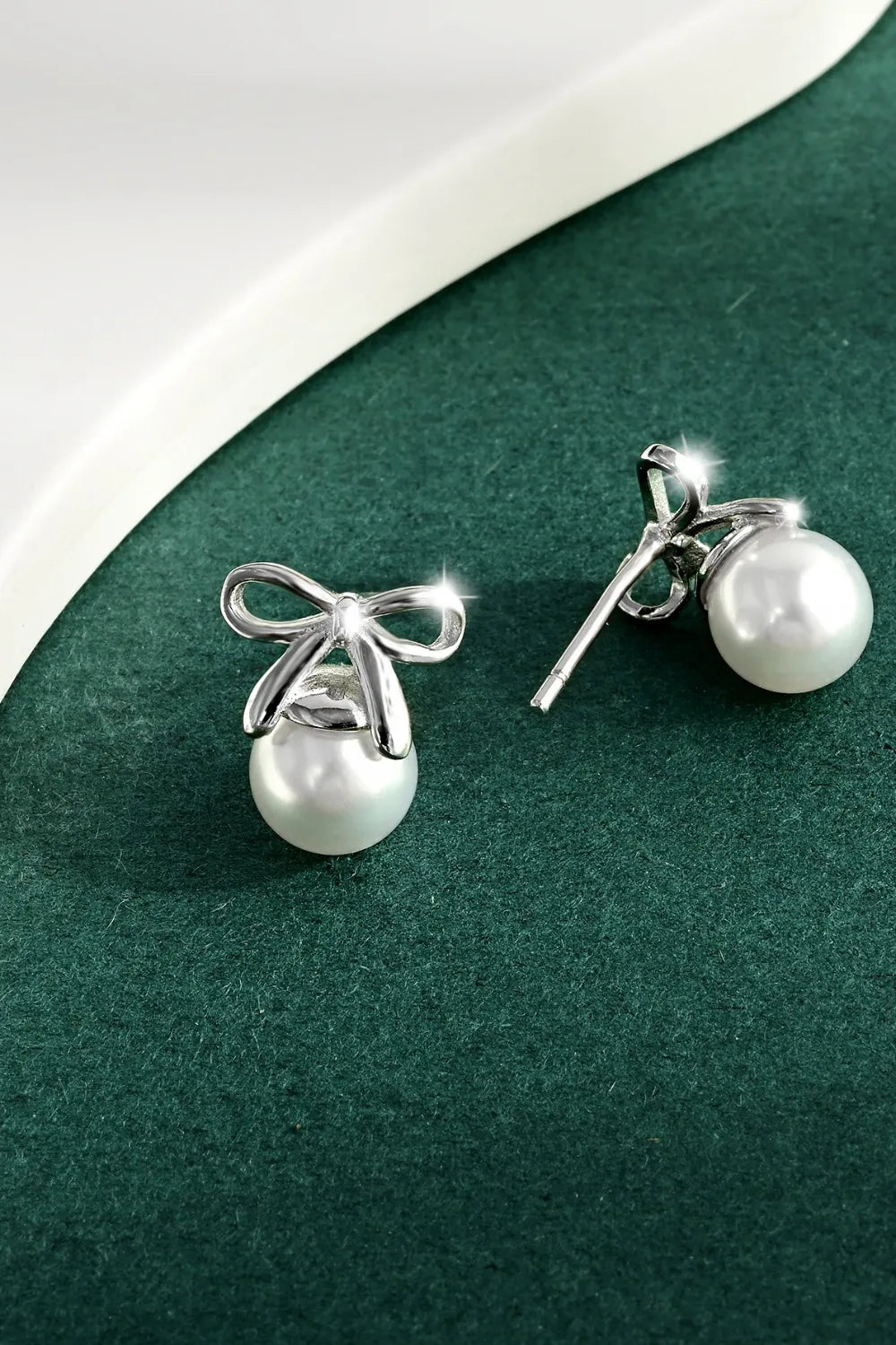 Silver bow pearl drop earrings with a polished finish.