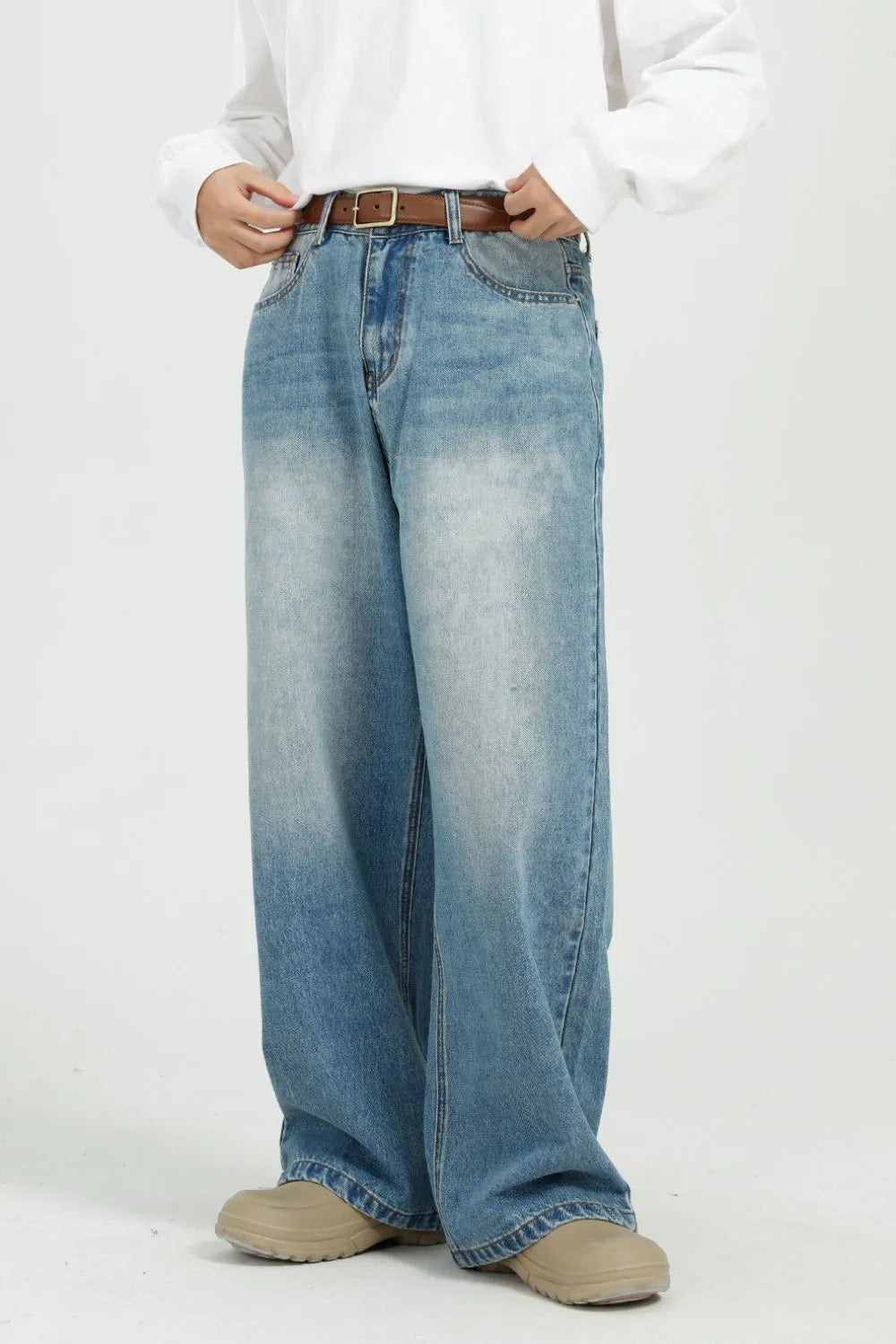 Wide-leg denim jeans in medium wash with pockets and a brown belt.