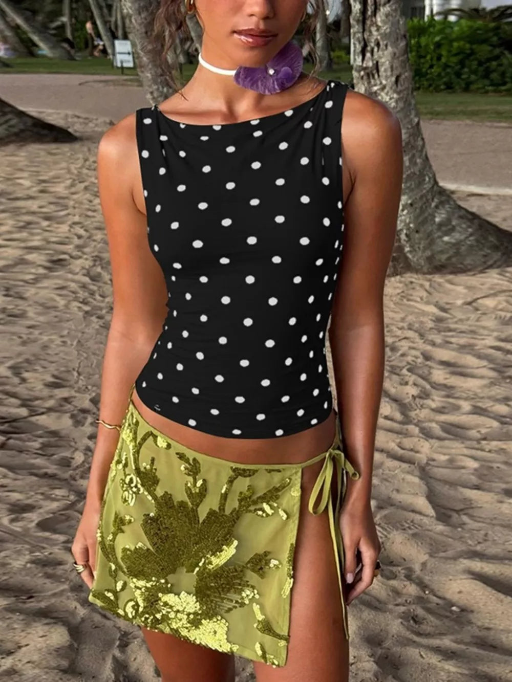 Black polka dot tank top with a scoop neck, paired with a green sequined mini skirt.