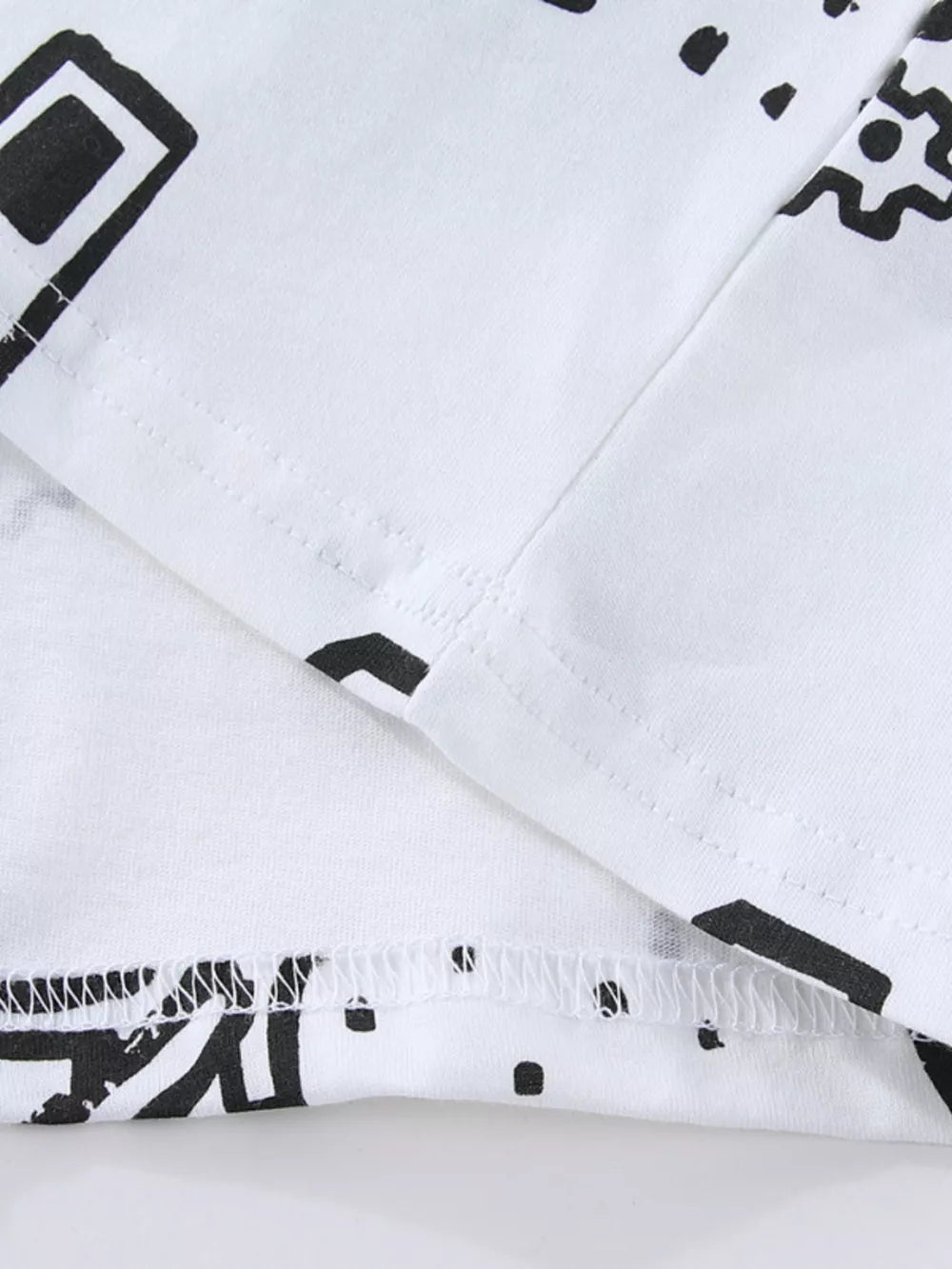 White cotton kids' t-shirt with black geometric construction vehicle print and stitched hem.