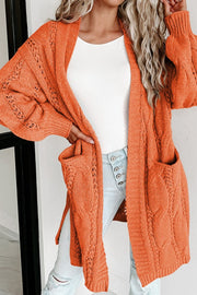 Burnt Coral cable knit open-front cardigan with pockets and detailed sleeves.