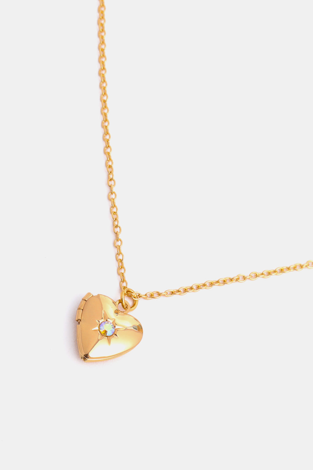 Gold heart locket necklace with a starburst detail and iridescent gem.