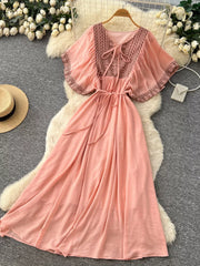 Pink embroidered V-neck maxi dress with flutter sleeves and tie waist.