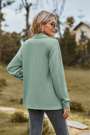 Sage green textured knit polo shirt with long sleeves and a collared neckline.
