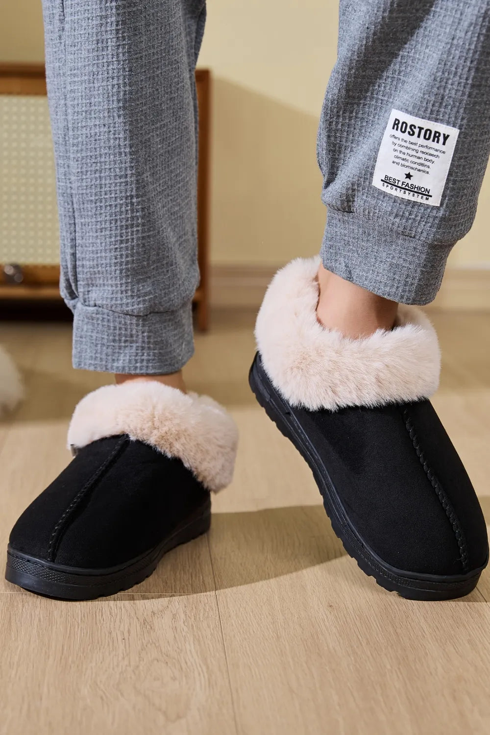 Black suede house slippers with plush shearling trim.