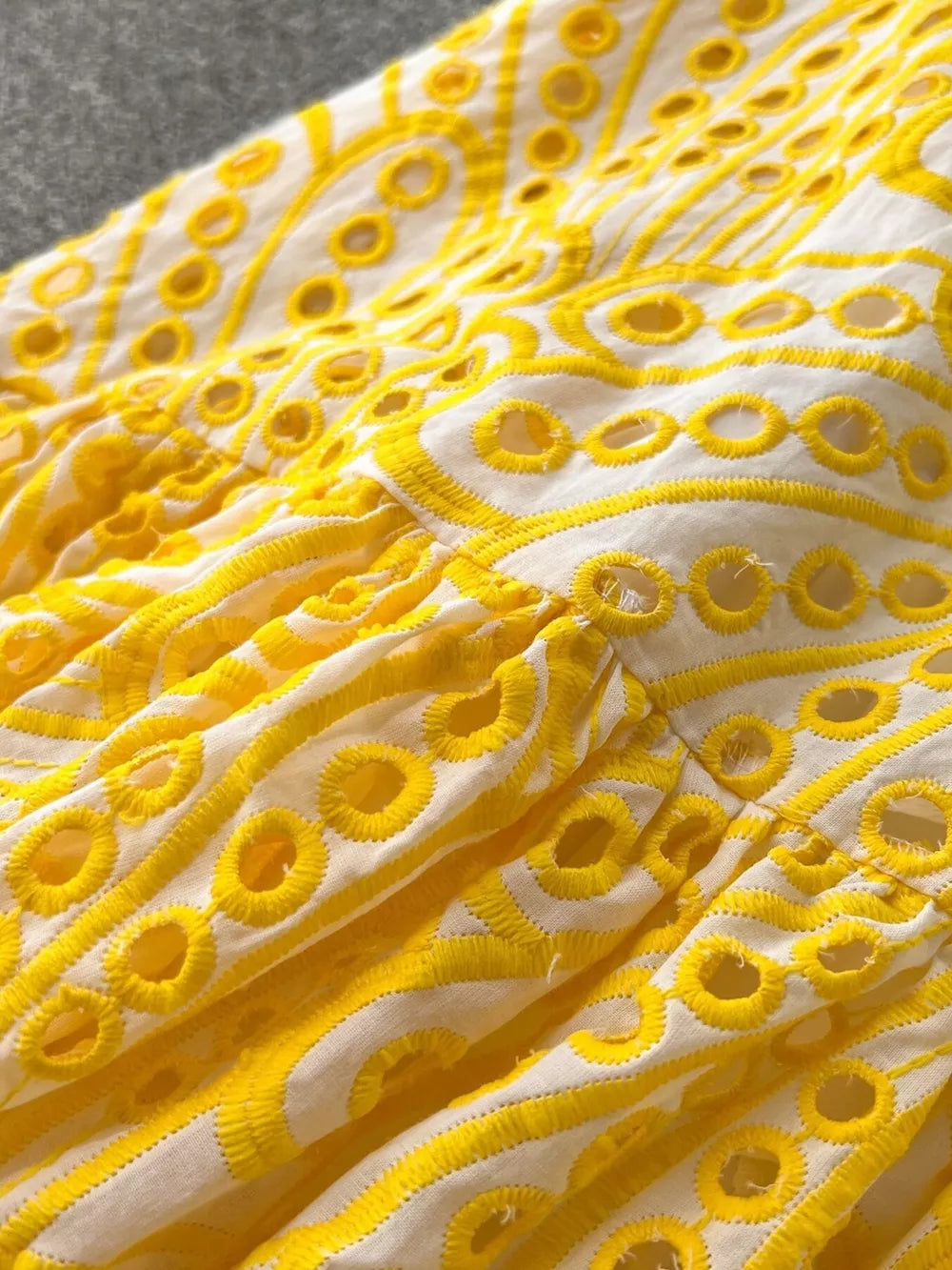 Yellow lace-embroidered tiered cami dress with eyelet details and ruffled tiers.