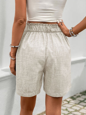 Beige linen shorts with elastic waistband and pleat front detail.