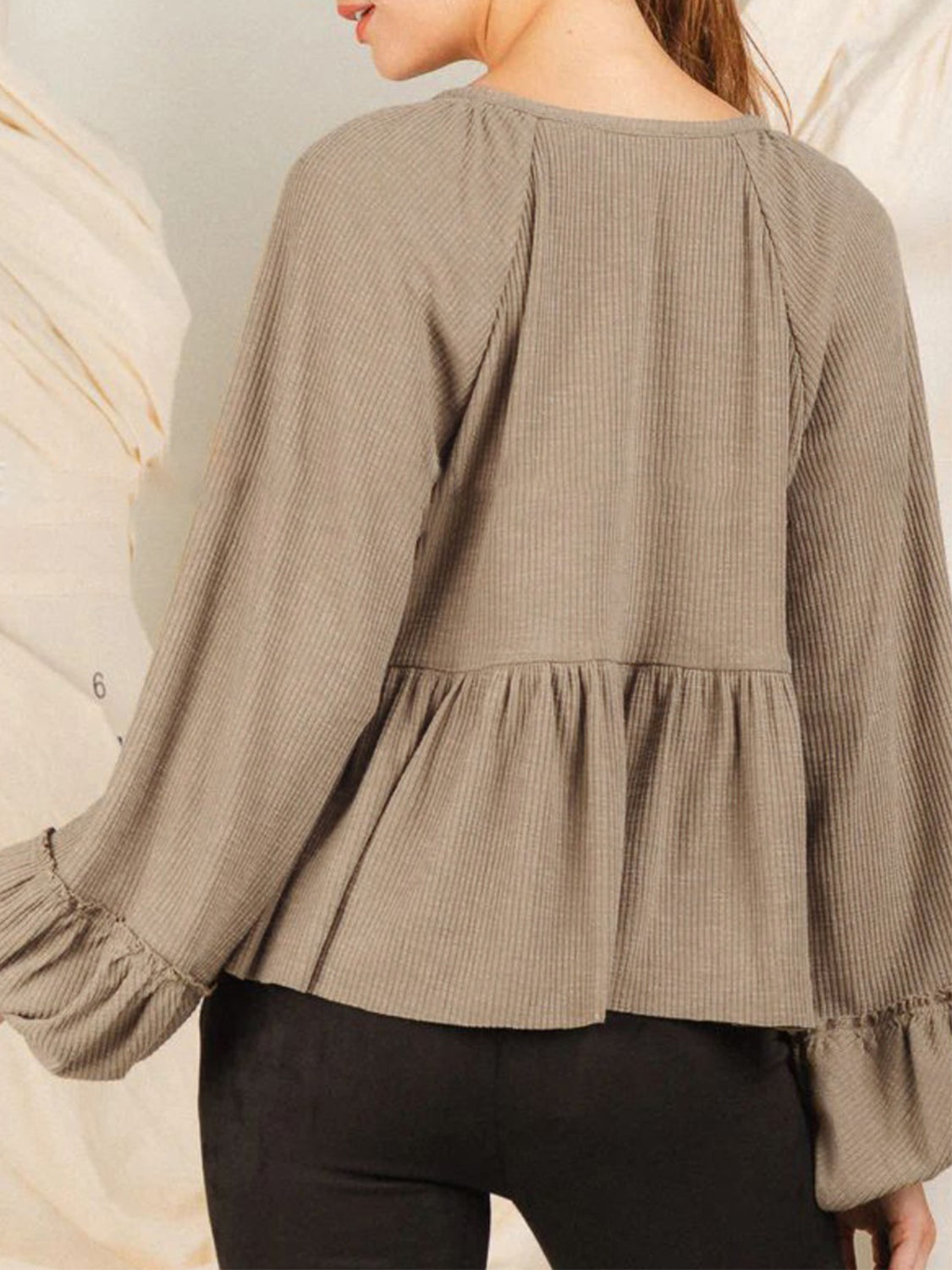 Tan ribbed peplum blouse with ruffled cuffs and long sleeves.