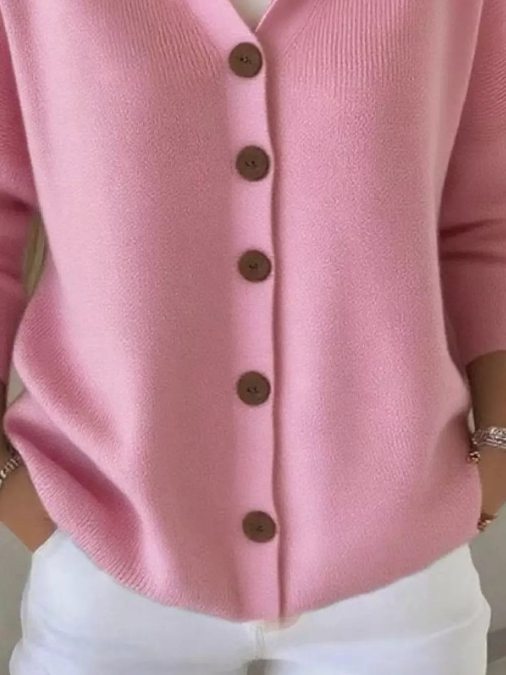 Pink button-front knit cardigan with wooden buttons and ribbed details.