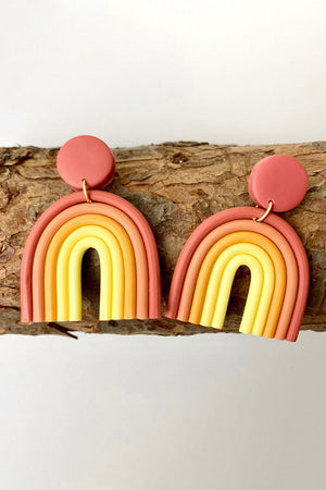 Rainbow arch clay earrings in coral, orange, and yellow with a round stud.