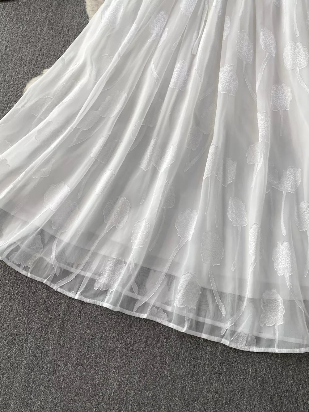 White chiffon maxi dress with floral embroidery and a belted waist.