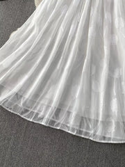White chiffon maxi dress with floral embroidery and a belted waist.