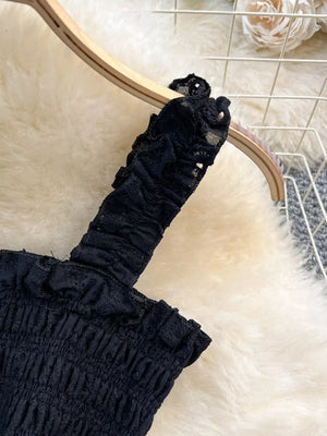 Black ruffled crop top with eyelet trim detail.
