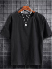 Black cotton crew neck t-shirt with short sleeves and a simple pendant necklace.