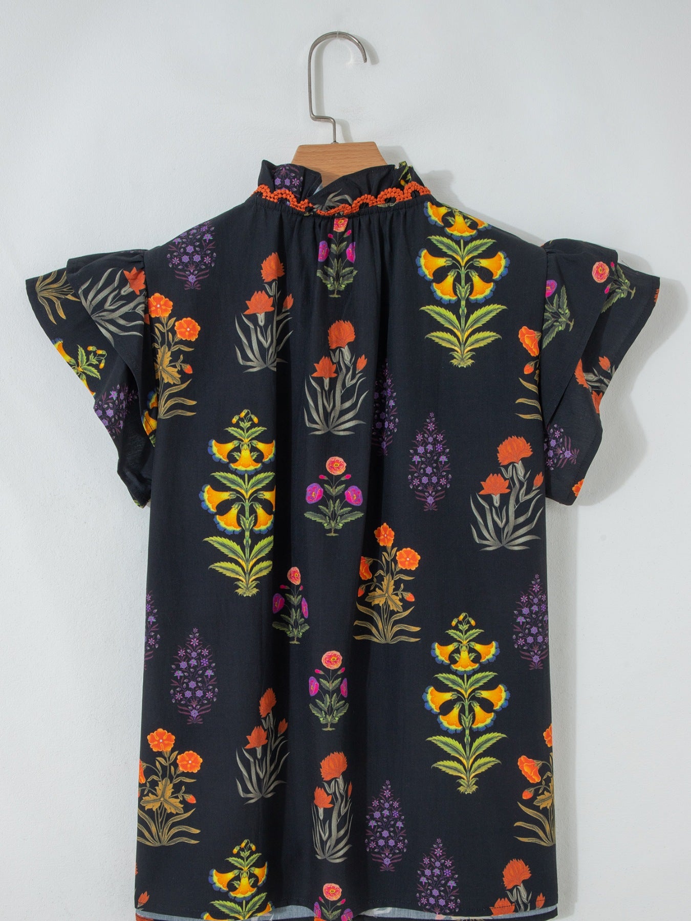Black cotton maternity shirt with colorful floral print, ruffled short sleeves, and a frilled V-neckline.