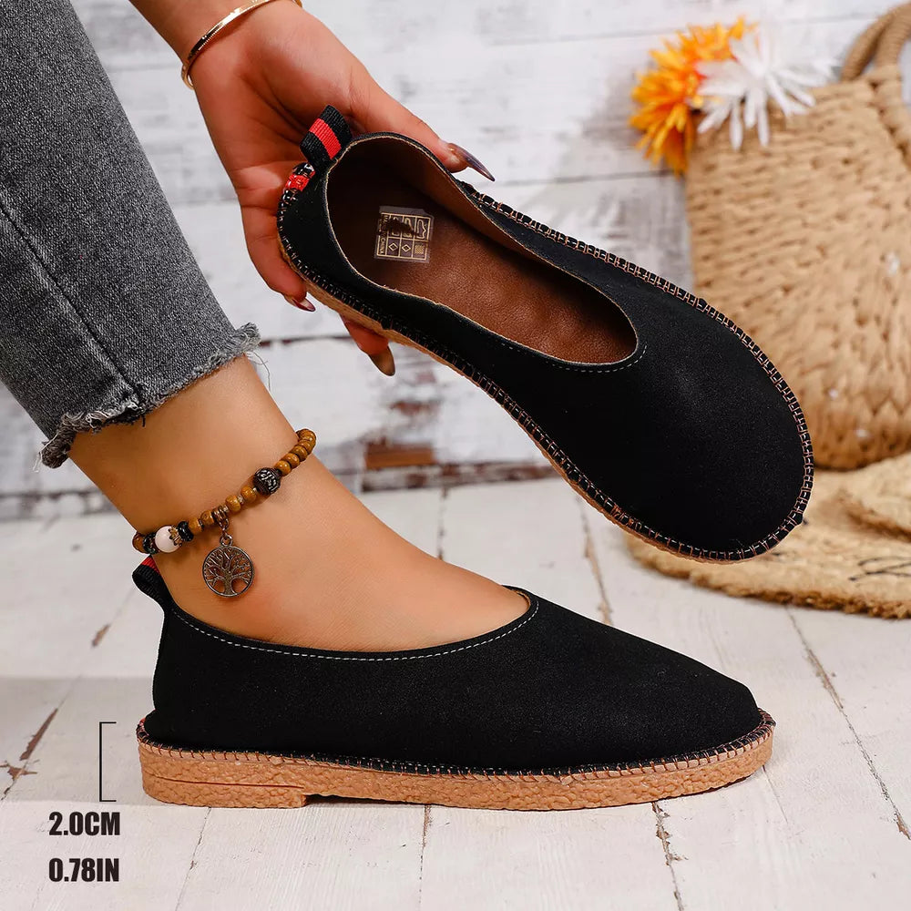 Black round toe comfort flats with contrast stitching and a textured sole.