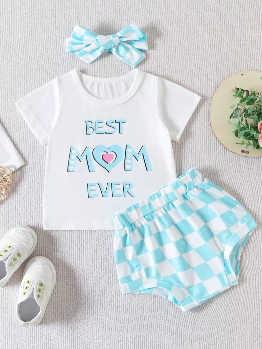 White graphic tee with "Best Mom Ever" text and blue gingham shorts set with matching headband.