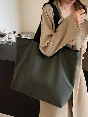 Minimalist large green shoulder bag with subtle embossed text detail.