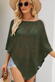Dark green open-knit poncho top with asymmetric hem and boat neckline, styled casually.