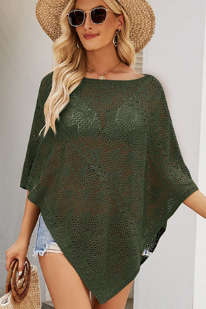 Dark green open-knit poncho top with asymmetric hem and boat neckline, styled casually.