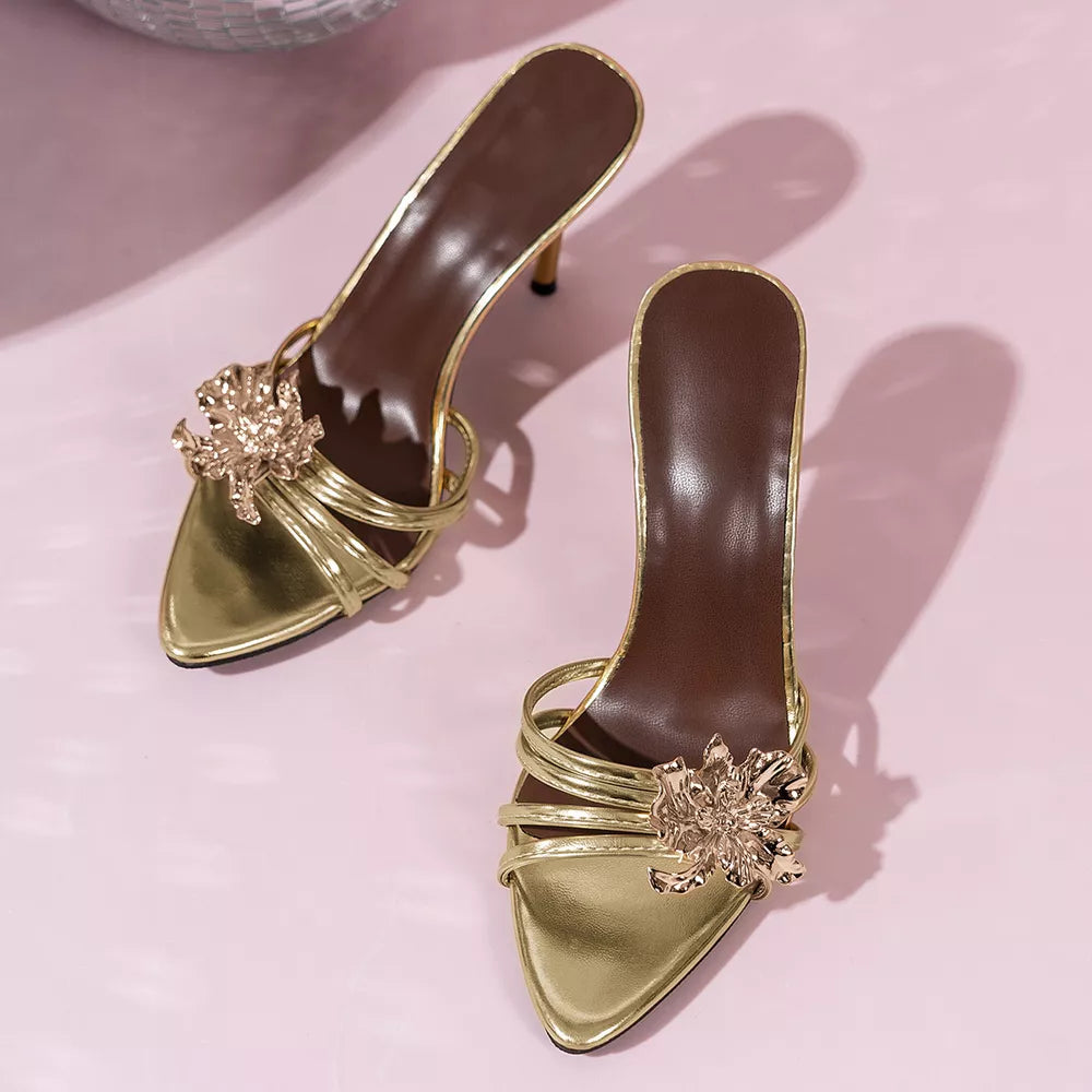 Gold high heel sandals with delicate straps and a floral embellishment.